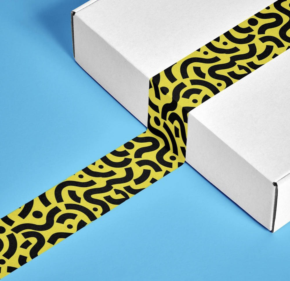 flat white box with a uniquely patterned yellow tape across it