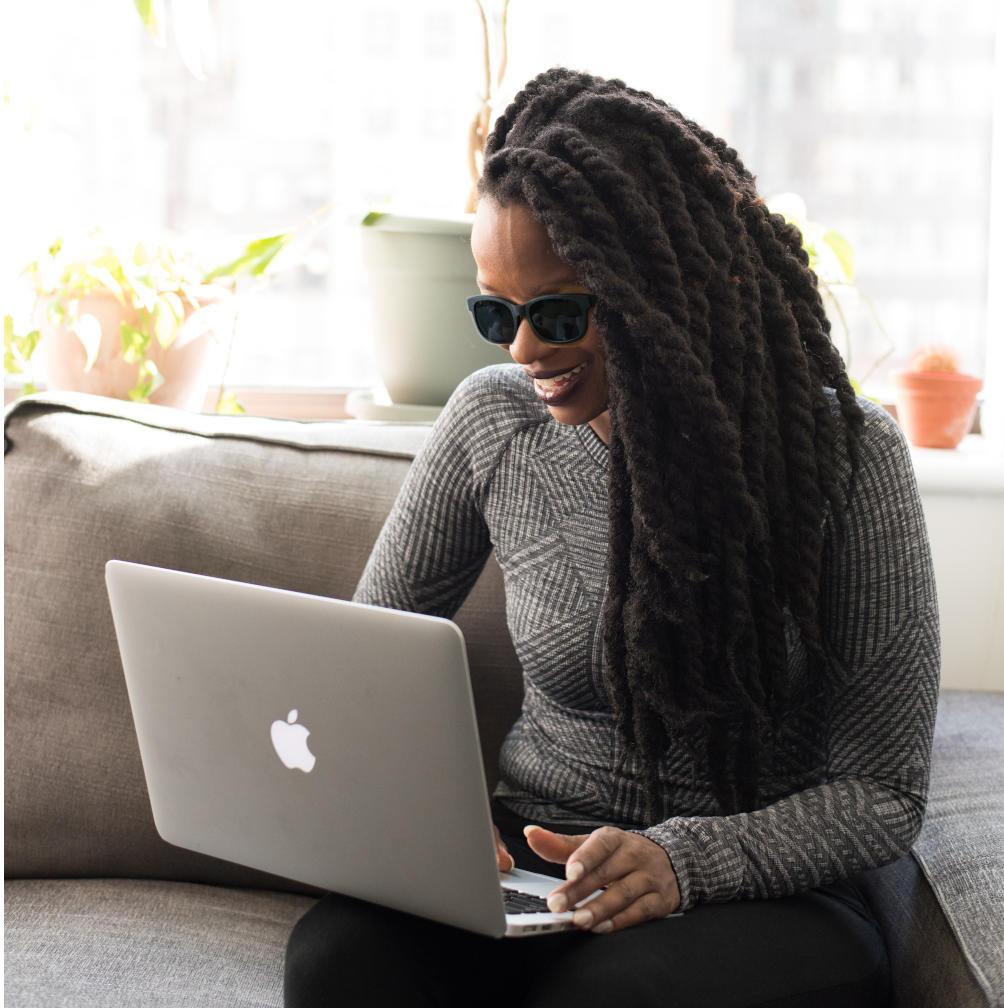 blind lady with dark glasses using a laptop and smiling
