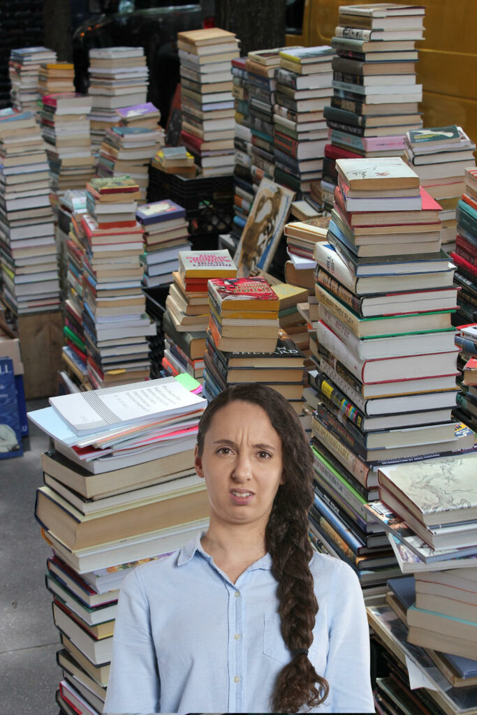 confused-looking lady standing in front of a huge pile of books