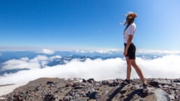 girl standing on a mountain top looking across neighboring the cloud-wreathed peaks