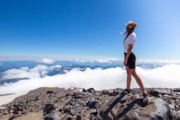 girl standing on a mountain top looking across neighboring the cloud-wreathed peaks